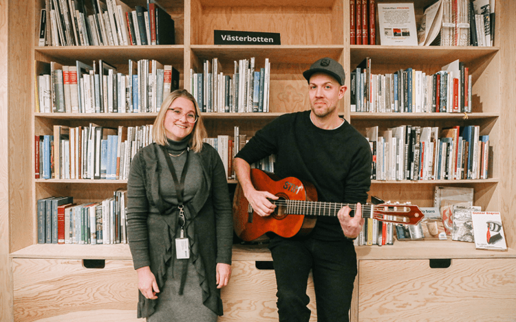 Kille och tjej med gitarr på bibliotek