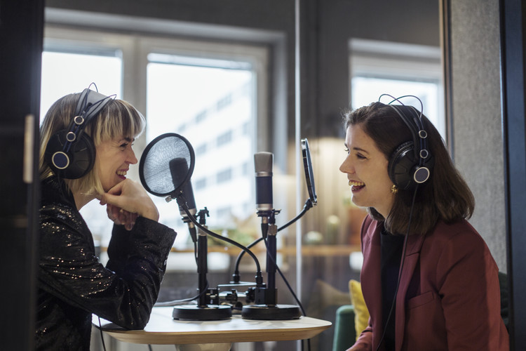 Två kvinnor som skrattar och spelar in podcast